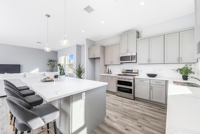 kitchen with sink, gray cabinets, hanging light fixtures, and stainless steel appliances