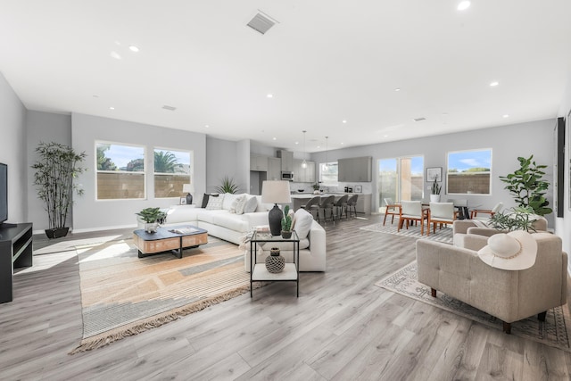 living room with light wood-style floors, baseboards, visible vents, and recessed lighting