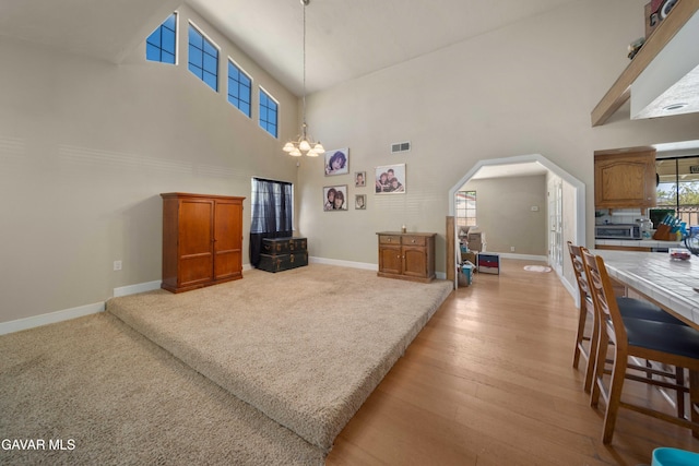 2747 Wilson Ct, Lancaster, CA 93536 - living area featuring a high ceiling, arched walkways, a chandelier, and light wood-type flooring