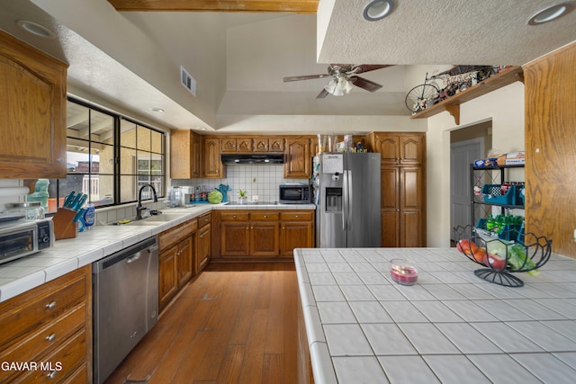2747 Wilson Ct, Lancaster, CA 93536 - kitchen with stainless steel appliances, tile countertops, brown cabinetry, recessed lighting, and a textured ceiling