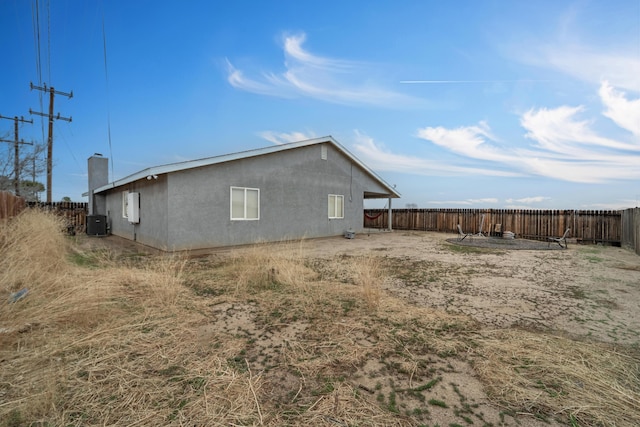 view of side of home featuring a fenced backyard, central AC, and stucco siding