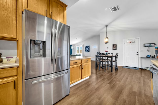 kitchen featuring visible vents, vaulted ceiling, light countertops, stainless steel fridge, and dark wood finished floors