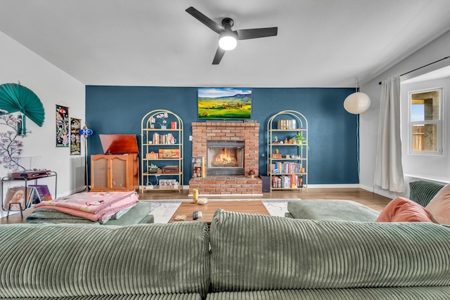 living area featuring a brick fireplace, ceiling fan, baseboards, and wood finished floors