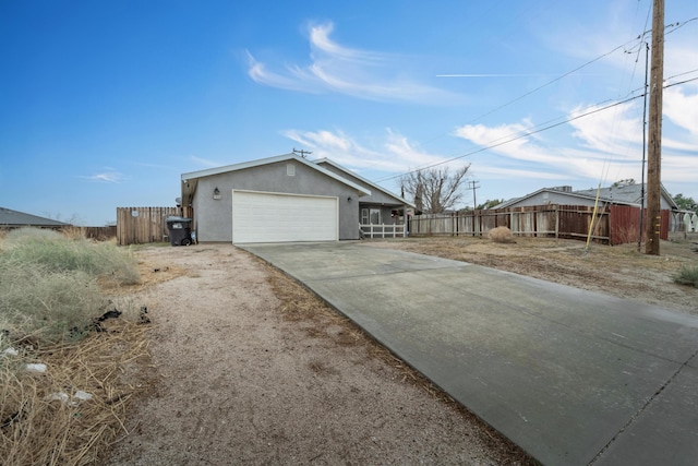 view of front of house with an attached garage, fence, concrete driveway, and stucco siding