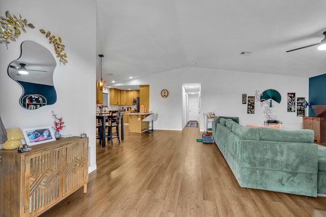 living room with ceiling fan, visible vents, baseboards, vaulted ceiling, and light wood-style floors