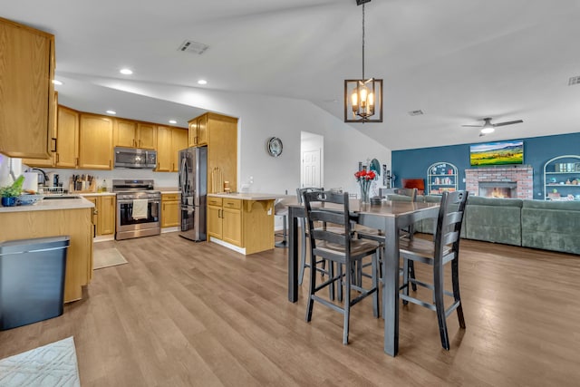 dining space featuring lofted ceiling, a brick fireplace, light wood-style flooring, and visible vents