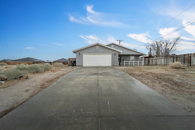 view of front facade with a garage, fence, driveway, and stucco siding