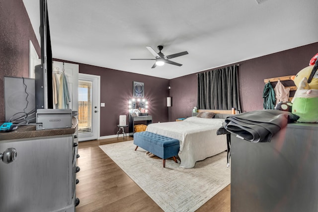 bedroom featuring a ceiling fan, access to outside, baseboards, and wood finished floors