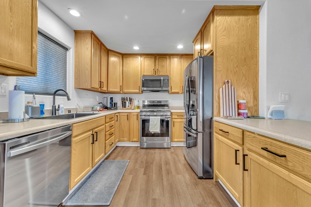 kitchen featuring light wood-style flooring, appliances with stainless steel finishes, a sink, and recessed lighting