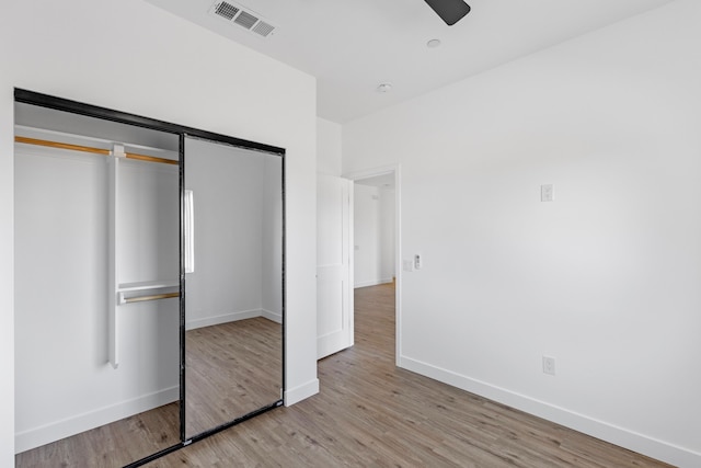 unfurnished bedroom with baseboards, visible vents, light wood-style flooring, ceiling fan, and a closet