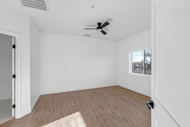 empty room featuring wood finished floors, visible vents, and ceiling fan