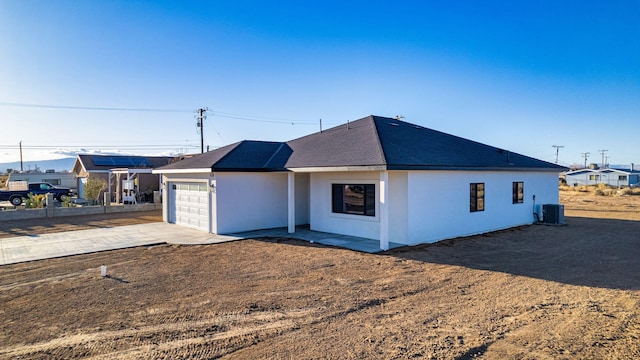 exterior space with a garage, central AC, driveway, and stucco siding