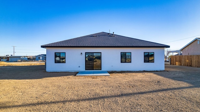 rear view of house with a shingled roof and fence