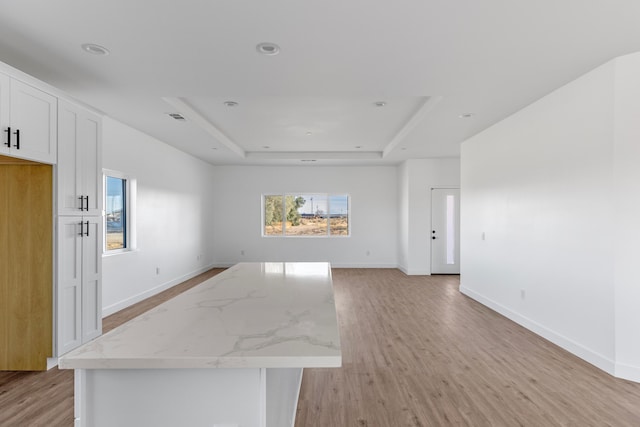 empty room featuring a tray ceiling, recessed lighting, baseboards, and light wood finished floors