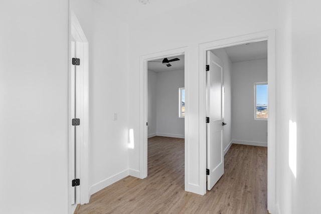 corridor with baseboards and light wood-style floors