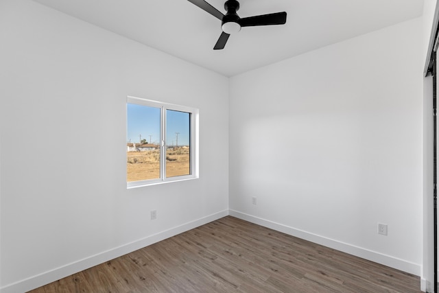 empty room featuring a ceiling fan, baseboards, and wood finished floors