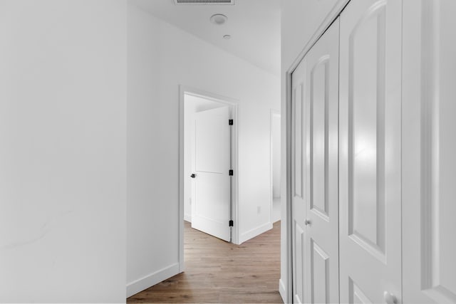 hall featuring visible vents, light wood-style floors, and baseboards