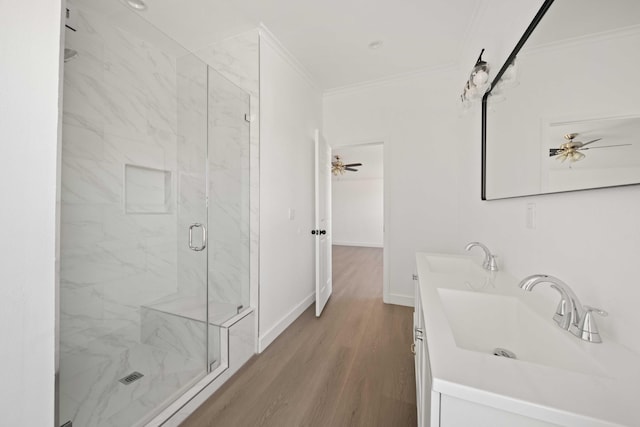 bathroom with ceiling fan, hardwood / wood-style floors, vanity, a shower with shower door, and ornamental molding