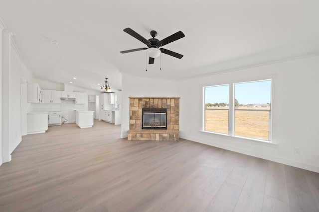 unfurnished living room with a stone fireplace, light wood-type flooring, vaulted ceiling, ceiling fan with notable chandelier, and ornamental molding