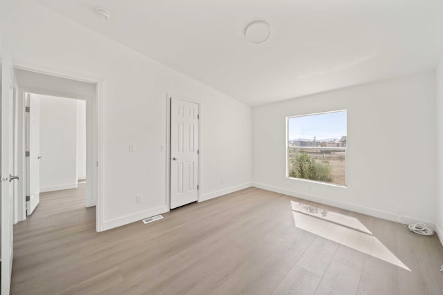 spare room with light hardwood / wood-style flooring and lofted ceiling