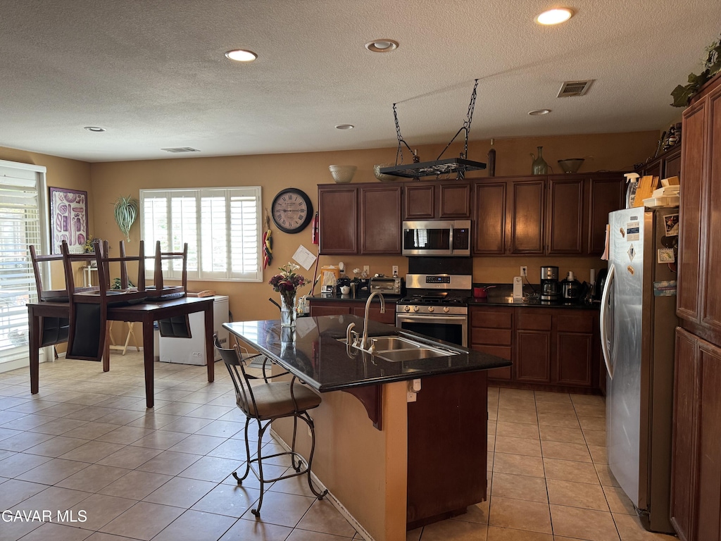39300 Kennedy Dr, Palmdale, CA 93551 - kitchen featuring stainless steel appliances, dark countertops, a textured ceiling, light tile patterned floors, and recessed lighting