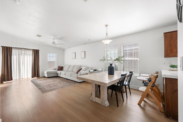 dining area with a ceiling fan, visible vents, light wood finished floors, and baseboards