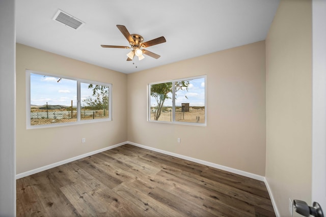 unfurnished room featuring baseboards, visible vents, and wood finished floors