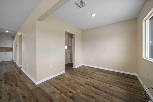 unfurnished room with attic access, visible vents, wood finished floors, and baseboards
