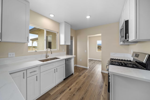 kitchen featuring white cabinets, light wood-style floors, appliances with stainless steel finishes, and a sink