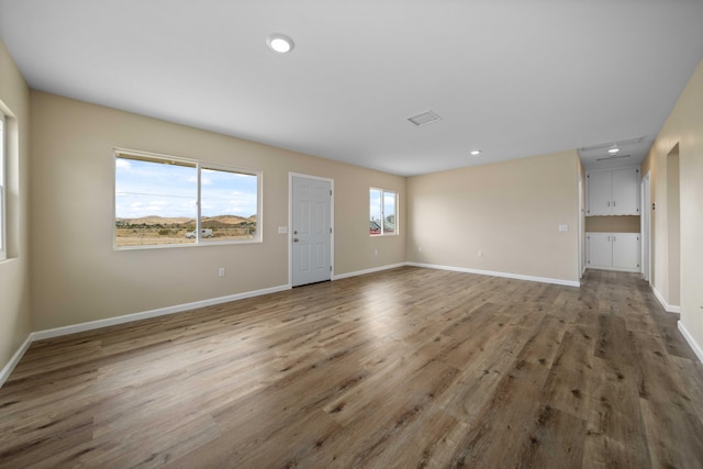 unfurnished living room featuring baseboards, recessed lighting, and wood finished floors