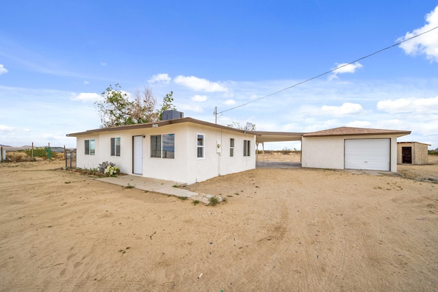 exterior space with dirt driveway, an outbuilding, and stucco siding