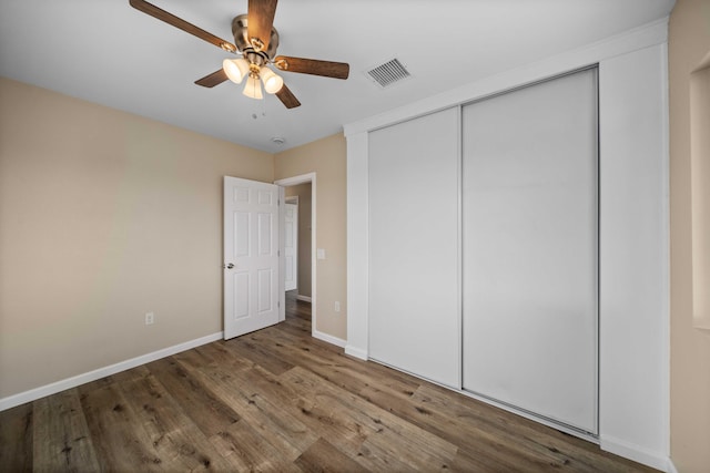 unfurnished bedroom featuring a closet, wood finished floors, visible vents, a ceiling fan, and baseboards
