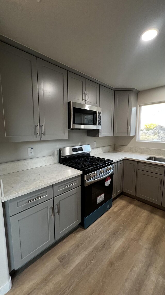 kitchen featuring gray cabinets, light hardwood / wood-style flooring, stainless steel appliances, and sink