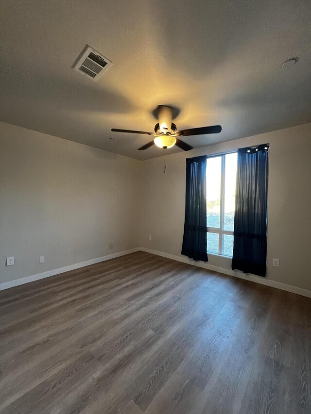 empty room with dark hardwood / wood-style flooring, a water view, and ceiling fan