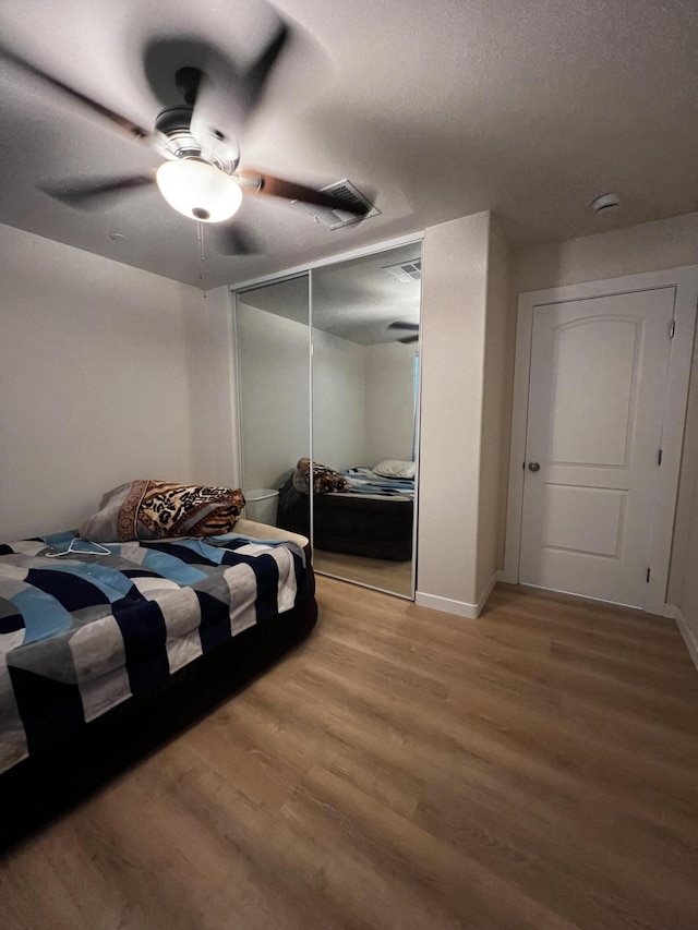 bedroom with hardwood / wood-style floors, a textured ceiling, a closet, and ceiling fan