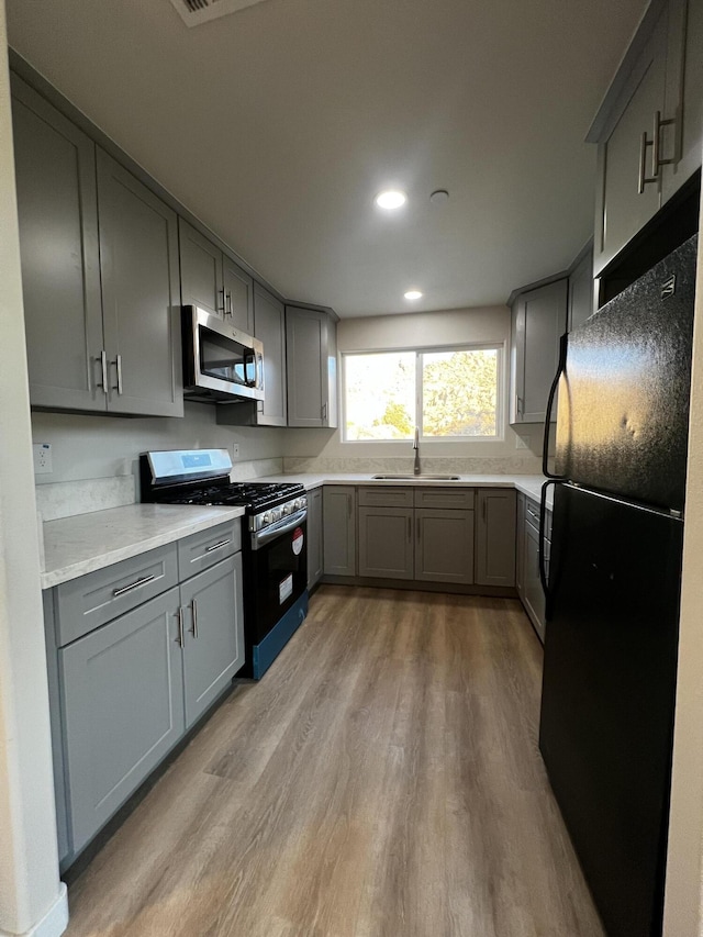 kitchen featuring gray cabinets, sink, black appliances, and light hardwood / wood-style floors