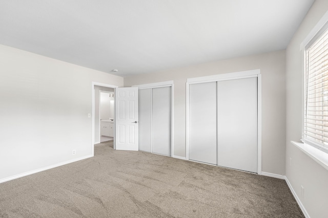 unfurnished bedroom with multiple closets and carpet flooring