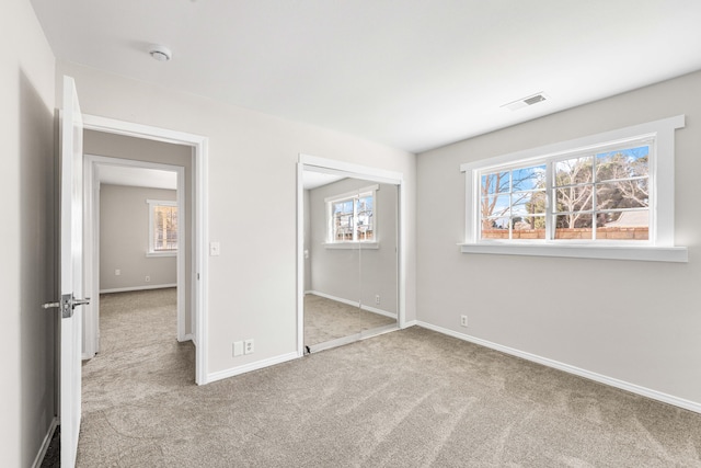 unfurnished bedroom with light colored carpet and a closet