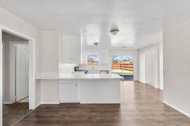 kitchen with dark wood-type flooring, kitchen peninsula, sink, and white cabinets