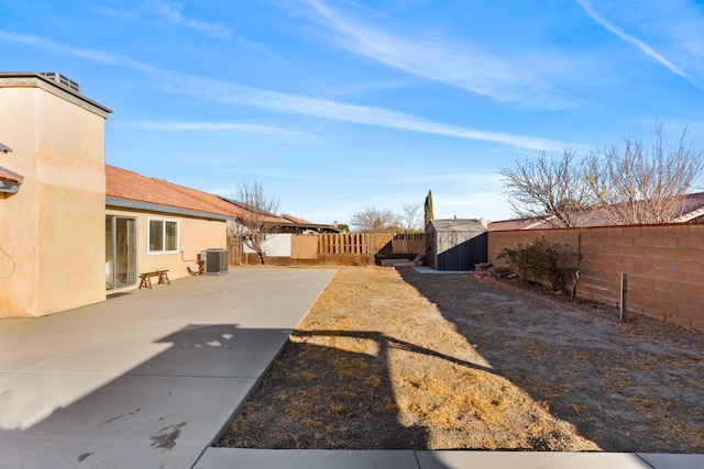 view of yard with a storage unit, cooling unit, and a patio area