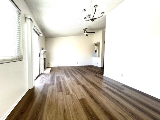 unfurnished living room featuring lofted ceiling, ceiling fan with notable chandelier, sink, a textured ceiling, and light tile patterned flooring