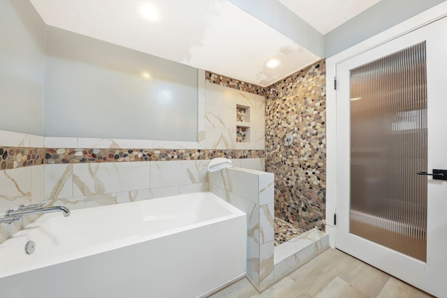 full bath featuring a garden tub, tile walls, and tiled shower