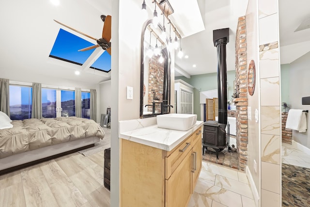 bathroom with vanity, visible vents, a wood stove, ceiling fan, and ensuite bathroom