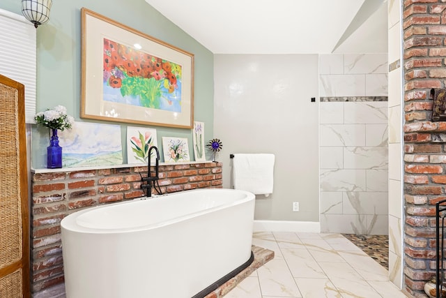 bathroom with baseboards, a freestanding bath, lofted ceiling, tiled shower, and marble finish floor