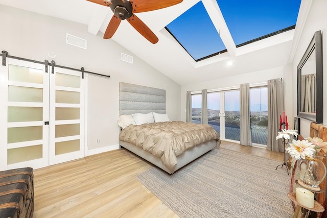 bedroom featuring a barn door, lofted ceiling, visible vents, and wood finished floors