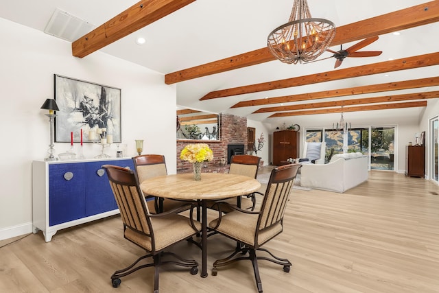 dining space featuring visible vents, a brick fireplace, vaulted ceiling with beams, baseboards, and light wood-style floors