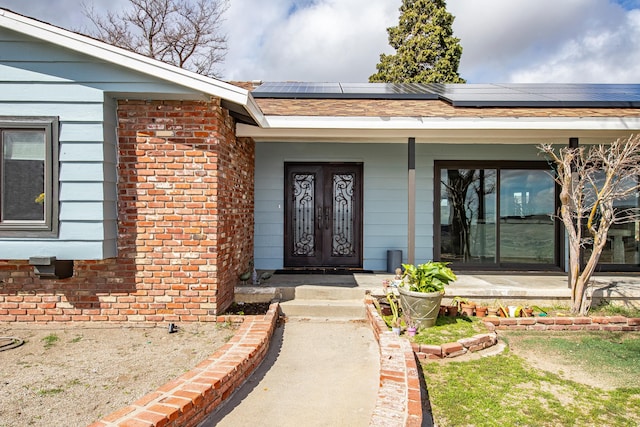 view of exterior entry featuring a porch, brick siding, and roof mounted solar panels