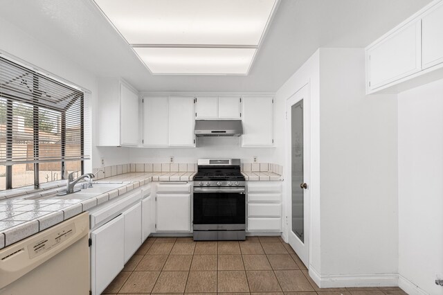 37756 E 45th St, Palmdale, CA 93552 - kitchen featuring stainless steel gas range, under cabinet range hood, white dishwasher, light tile patterned floors, and white cabinets