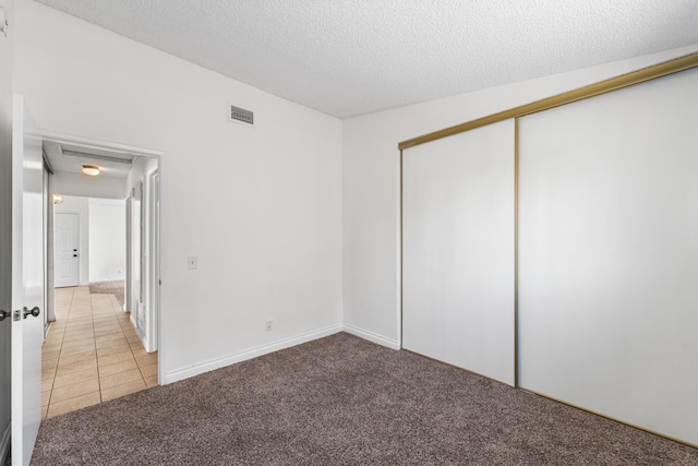 37756 E 45th St, Palmdale, CA 93552 - unfurnished bedroom featuring light carpet, a textured ceiling, a closet, and light tile patterned floors