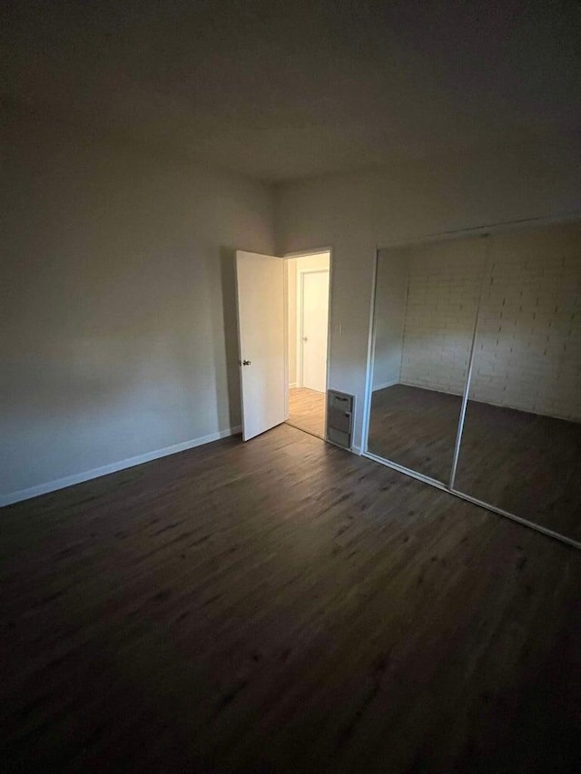 unfurnished bedroom with dark wood-type flooring and a closet